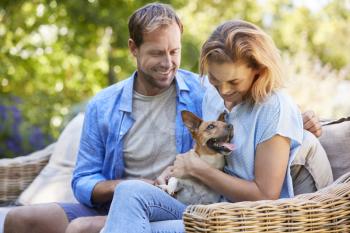 Happy young couple  sitting with their pet dog in the garden