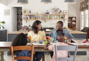 Black family of four having lunch in their kitchen at home