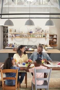 Black family of four having lunch in their kitchen, vertical