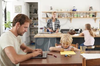 Young white family of four busy in their kitchen, close up