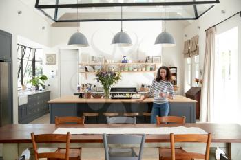 Mixed race woman in open plan kitchen looking to camera