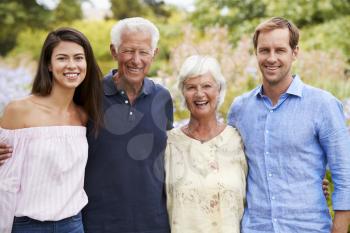 Portrait Of Senior Parents With Adult Children On Walk In Park