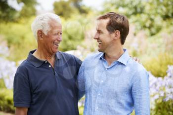 Senior Father With Adult Son On Walk In Park