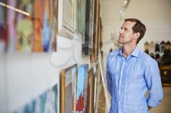 Man Looking At Paintings In Art Gallery
