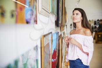 Woman Looking At Paintings In Art Gallery