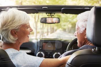 Senior Couple Drive Open Top Car On Countryside Road Trip