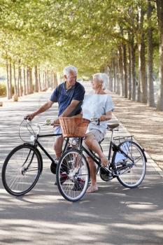 Smiling Senior Couple Cycling On Country Road