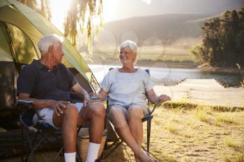 Senior Couple Enjoying Camping Vacation By Lake Together