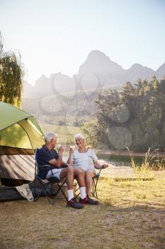 Senior Couple Enjoying Camping Vacation By Lake Making A Toast