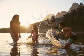 Family Enjoying Evening Swim In Countryside Lake