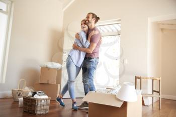 Happy Couple Surrounded By Boxes In New Home On Moving Day