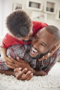 Son Climbs On Fathers Back As They Play Game In Lounge Together