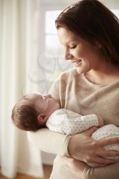Loving Mother Cuddling Newborn Baby At Home
