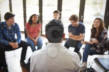 Rear View Of Male Tutor Leading Discussion Group Amongst High School Pupils