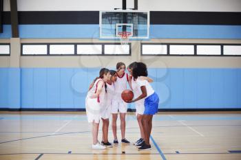 Female High School Basketball Players In Huddle Having Team Talk With Coach