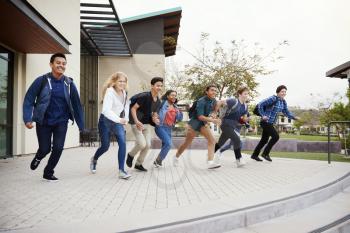 Group Of High School Students Running Towards Steps Outside College Buildings