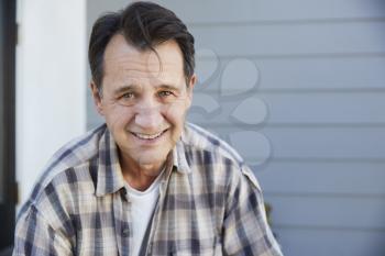 Portrait Of Senior Man Standing Outside Grey Clapboard House