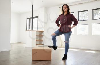 Portrait Of Proud Woman Standing On Box In New Home On Moving Day