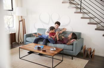 Family Having Fun Lying On Sofa At Home Together