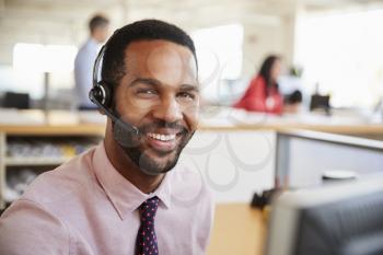 Man working in a call centre smiling to camera, close-up