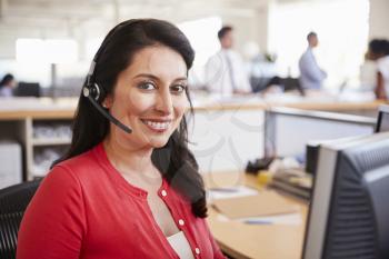 Hispanic woman working in a call centre smiling to camera