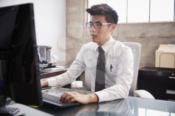 Young Asian businessman using a computer at an office desk