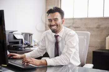 Young Hispanic businessman using computer smiling to camera