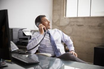 Mixed race businessman at an office desk using the phone