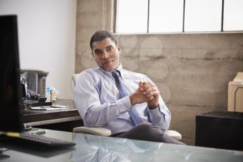 Mixed race businessman at an office desk looking to camera