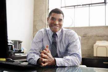 Mixed race businessman at an office desk smiling to camera