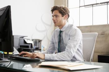 Young white businessman using a computer at an office desk