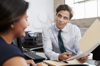 Young male professional shows documents to woman in meeting
