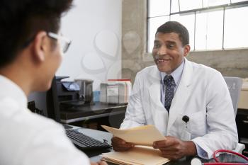 Mixed race male doctor holding documents in patient meeting