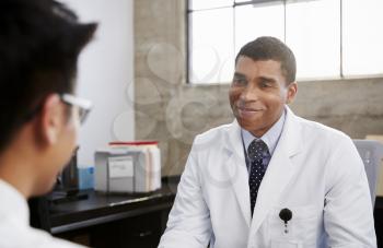 Smiling mixed race male doctor in consultation with patient