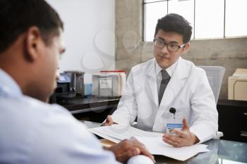 Young Asian male doctor in consultation with male patient