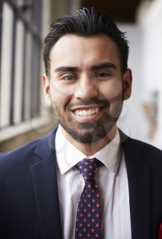 Young Hispanic businessman smiling to camera, vertical