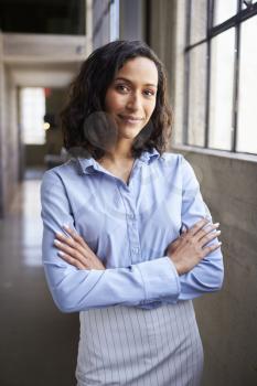 Young mixed race businesswoman standing with arms crossed