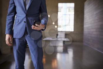 Mid section of man in blue suit using smartphone