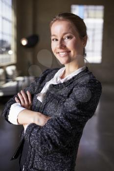 Young white businesswoman with arms crossed smiles to camera