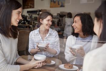 Four female friends relaxing over coffee at a coffee shop