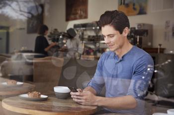 Young male customer using his smartphone in a coffee shop