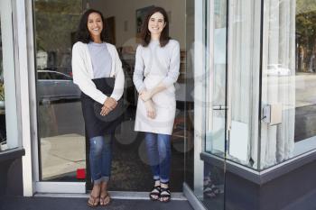 Two female business owners stand outside their coffee shop