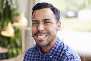 Young Hispanic man in coffee shop smiling to camera