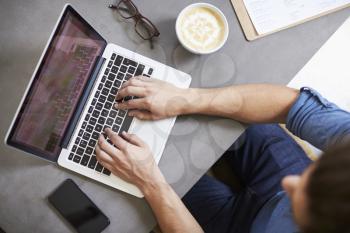 Caucasian man using laptop in a coffee shop, overhead shot