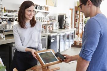 Male customer makes payment by smartphone at a coffee shop
