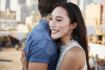 Couple Embracing On Rooftop Terrace With City Skyline In Background