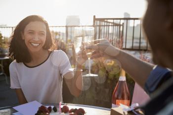 Couple Making Toast To Celebrate Birthday On Rooftop Terrace With City Skyline In Background