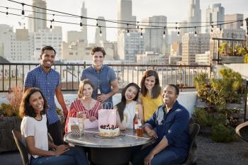 Portrait Of Friends Gathered On Rooftop Terrace To Celebrate Birthday With City Skyline In Background