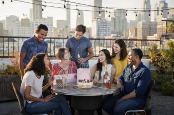 Friends Gathered On Rooftop Terrace To Celebrate Birthday With City Skyline In Background