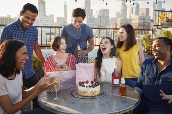 Friends Gathered On Rooftop Terrace To Celebrate Birthday With City Skyline In Background